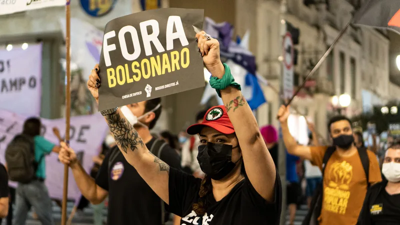 Demonstrators protesting against Bolsonaro, holding signs on a city street.